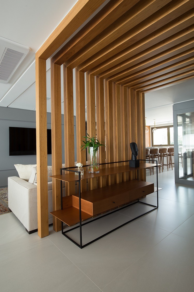 Observe o recurso de arquitetura de interiores criado para gerar um hall de entrada mantendo a fluidez da área social. O aparador é design de Bruno Faucz